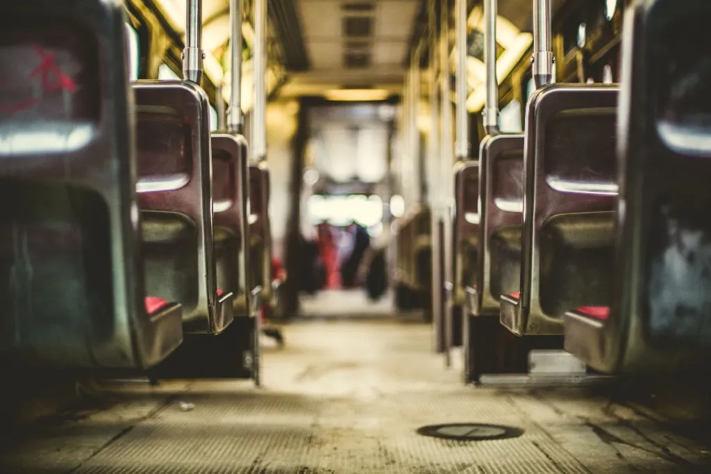 The aisle of an empty bus, seats receding towards the front
