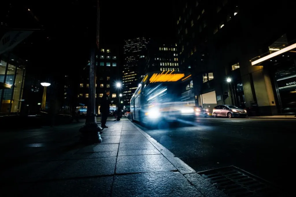 A long exposure of a bus pulling away on a city street at night