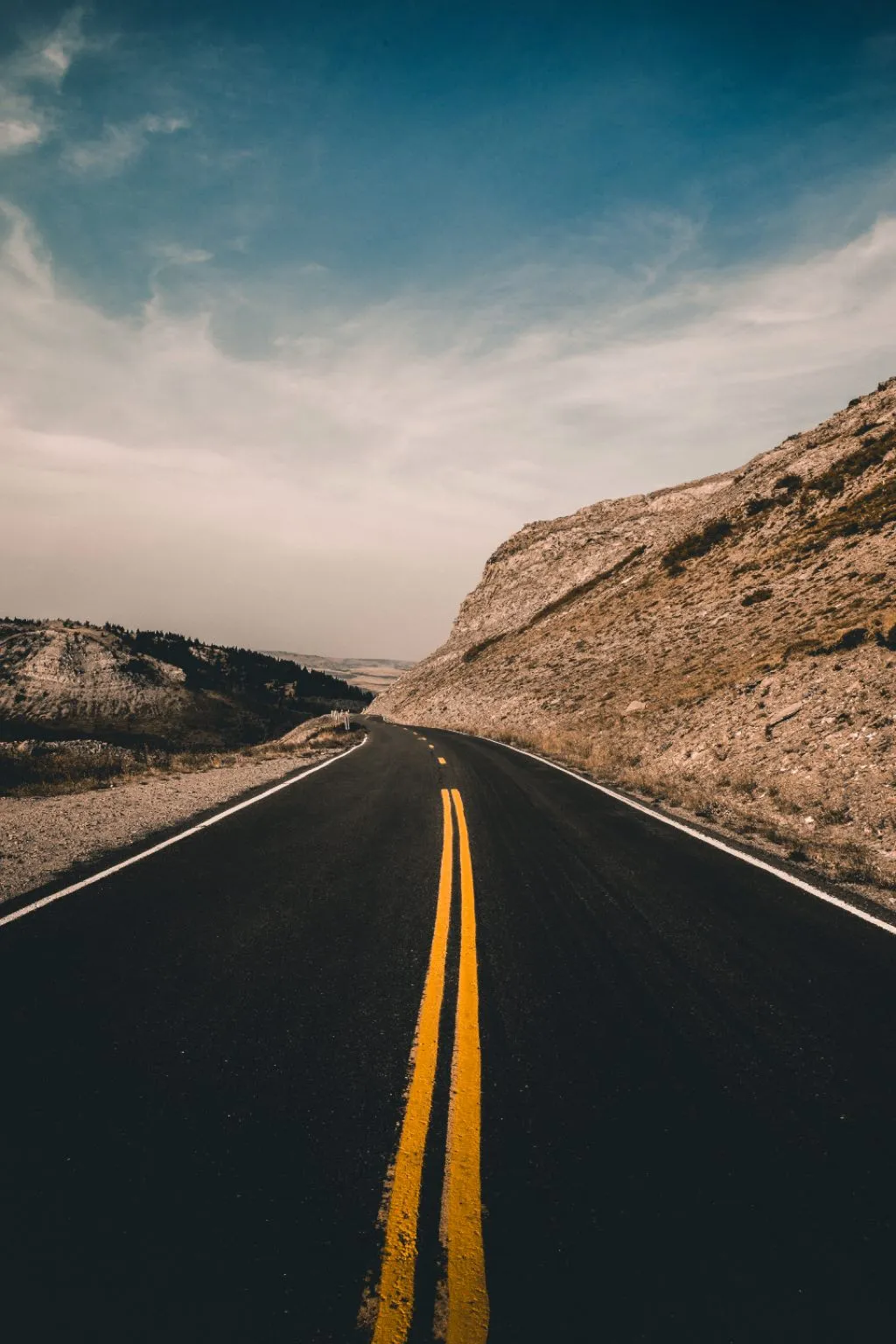 An open road running towards a hillside under a pale sky