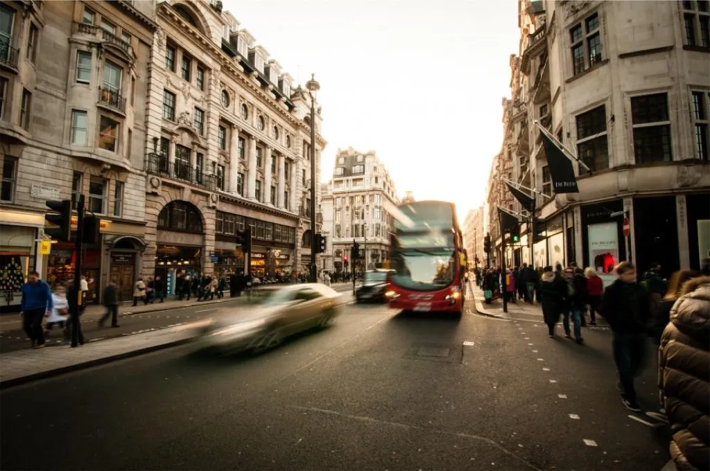 A busy city street at dusk, a bus moving through the traffic
